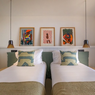 Sink into crisp linens and vibrant art in your peaceful twin bedroom, where pendant lighting creates perfect reading ambiance.