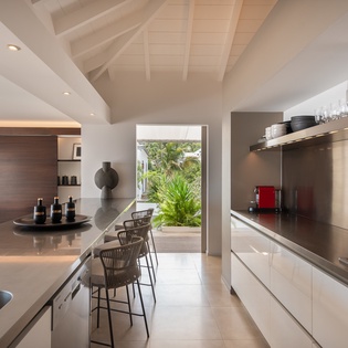 Step into your gourmet kitchen with sleek modern design, vaulted ceilings, and a stunning view of tropical greenery. Everything you need to create memorable meals during your stay.