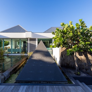 Modern villa featuring striking triangular water feature and sophisticated outdoor design with natural stone walls.