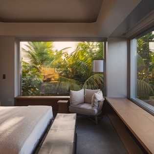 Wake up to lush tropical views through floor-to-ceiling windows in your serene bedroom sanctuary.