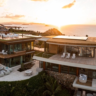 Stunning contemporary property with multi-level terraces overlooking pristine coastline, featuring modern architecture and breathtaking sunset views.