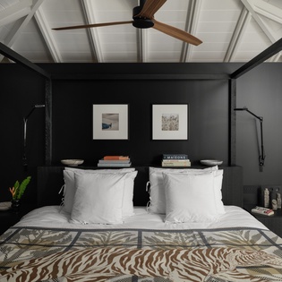 Unwind in your chic bedroom with dramatic black walls and exposed beams, where comfort meets contemporary design.