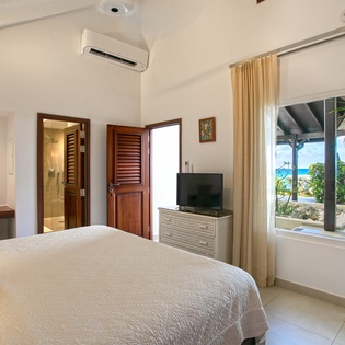 Wake up to ocean views and tropical breezes in your bright, air-conditioned bedroom. Step out to explore the beach, just steps from your door—your perfect island escape awaits.