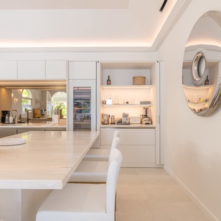 Your sleek modern kitchen features pristine white surfaces and ambient lighting, creating the perfect space for culinary adventures during your stay.