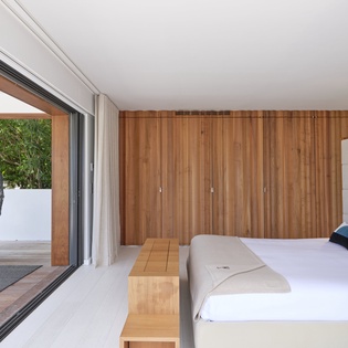 Step into your serene bedroom retreat with crisp white linens, warm wood accents, and a private terrace with a hammock chair overlooking lush greenery—your perfect escape awaits.