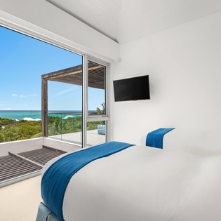 Wake up to stunning ocean views through your private terrace doors in this serene bedroom sanctuary.