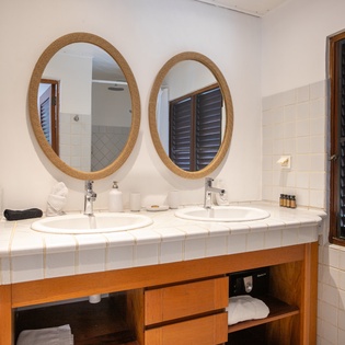 Start your morning refreshed at the dual vanities—elegant oval mirrors, white tile accents, and thoughtful touches like fresh towels and island-style shutters create your serene retreat.