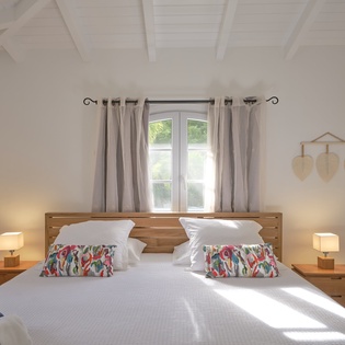 Drift off in your serene bedroom where natural light streams through windows, highlighting crisp linens and colorful accent pillows on your comfortable bed.