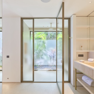 Step into your spa-like bathroom sanctuary with floor-to-ceiling windows revealing tropical views and luxurious marble finishes throughout.