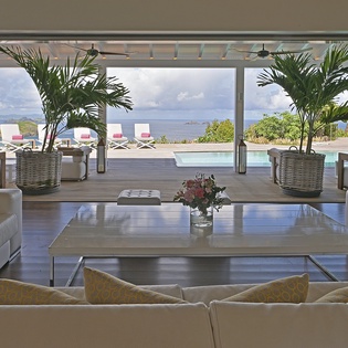 Relax in luxury as ocean views frame your serene living space, where poolside lounging awaits just beyond.