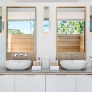 Your elegant ensuite features dual vessel sinks and sleek fixtures, with natural light streaming through windows for your morning routine.