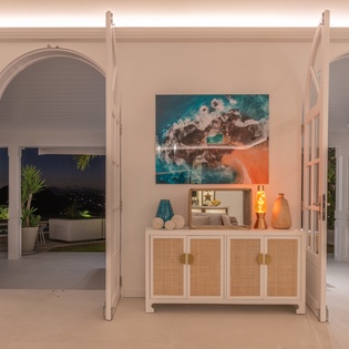 Step into your elegant tropical sanctuary where ocean-inspired artwork and warm lighting create the perfect atmosphere for your island getaway.