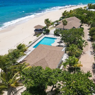 This exclusive beachfront property sits nestled between pristine white sands and lush tropical gardens, featuring a private pool and direct ocean access.