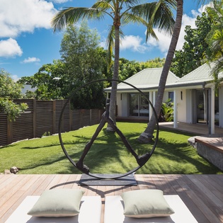 A stylish property with lush gardens, towering palms, and contemporary design beneath tropical skies.