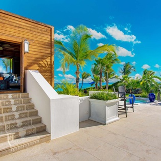 A tropical paradise awaits with stunning poolside views. Palm trees sway above pristine turquoise waters under bright Caribbean skies. The warm-toned entrance and lush surroundings set the stage for an unforgettable escape.