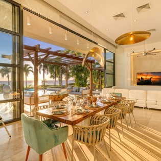 Your elegant dining space flows seamlessly to the terrace, where ocean views and tropical palms create the perfect backdrop for memorable meals.