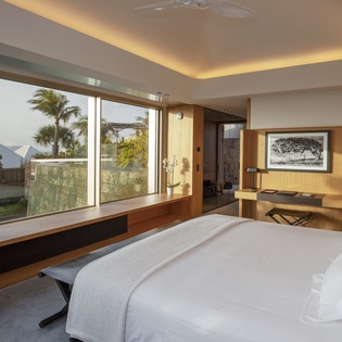 Wake up to panoramic views through floor-to-ceiling windows in your serene bedroom sanctuary with tropical gardens beyond.