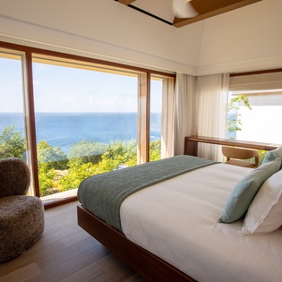 Wake up to breathtaking sea views from your king bed, where floor-to-ceiling windows frame endless blue horizons and lush tropical gardens below.
