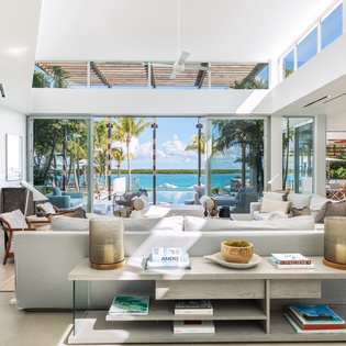 Your luxurious living space frames breathtaking ocean views through floor-to-ceiling windows, where turquoise waters meet pristine sands.