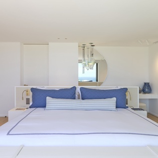 Drift into restful sleep in your sophisticated bedroom, where crisp white linens and calming blue accents create the perfect sanctuary for relaxation.