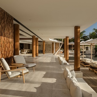 Relax in this stunning covered terrace with modern seating, where warm wood textures meet tropical views for your perfect island retreat.