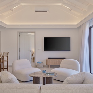 Relax in your bright, modern living space with plush seating, entertainment center, and peaceful garden views through floor-to-ceiling windows.