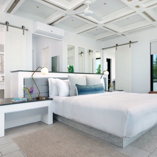 Sink into crisp linens on your king bed and unwind beneath stunning coffered ceilings. Wake up to lush garden views and enjoy the modern barn doors that give this bright, airy suite its coastal charm.