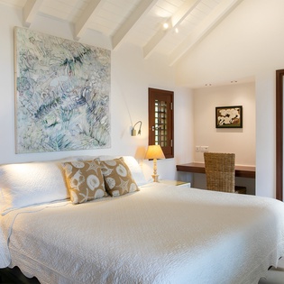 Sink into crisp, white linens beneath vaulted beamed ceilings that create an airy, peaceful retreat. Your private en-suite awaits just steps away, ready for a refreshing escape.