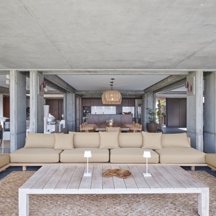 Settle into your spacious living area where concrete beams and warm wood create modern sophistication for memorable gatherings.