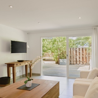 Your bright living room flows seamlessly to a peaceful garden terrace, where natural light and lush greenery create the perfect retreat.