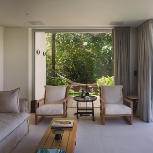 Relax in your stylish living room where floor-to-ceiling windows frame lush garden views and your private terrace beckons beyond.