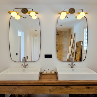 Dual vanities with modern fixtures and warm wood tones create a luxurious space for your morning and evening routines. The stylish mirrors and ambient lighting add a touch of elegance.