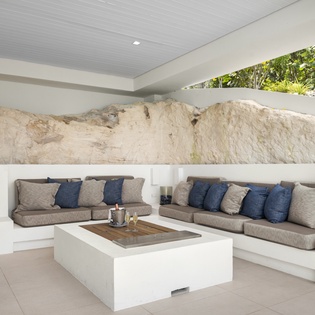 Unwind in your sleek seating area where modern comfort meets natural stone walls, creating the perfect sanctuary for relaxation.