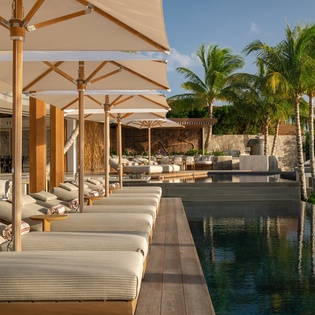 Luxurious poolside loungers with plush cushions await under elegant umbrellas, where you'll enjoy tropical paradise views and ultimate relaxation.