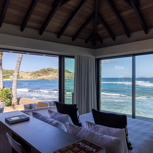 Wake up to stunning ocean views through floor-to-ceiling windows in your spacious living room, where turquoise waters meet the horizon.