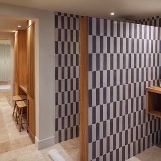 Modern spa changing area with geometric tiled walls, warm wood accents, and fresh towels ready for your wellness retreat.