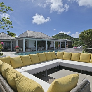 Unwind on your private terrace with stunning tropical views, where vibrant yellow cushions invite relaxation overlooking the sparkling pool.