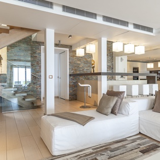 Sink into the plush white sectional and take in the dramatic spiral staircase and open kitchen beyond. Modern design meets warm stone textures to create your perfect retreat.