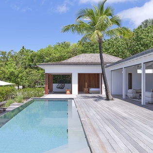 This tropical paradise features a pristine private pool surrounded by modern living spaces, sunbeds, and swaying palms—a secluded oasis where every detail invites pure relaxation under endless blue skies.