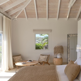 Sunlight pours through open doors and windows, bathing your peaceful retreat in natural warmth. Crisp white linens, natural textures, and soaring wood-beamed ceilings create a serene, inviting sanctuary.
