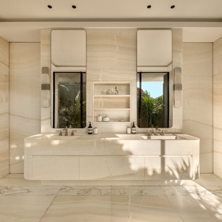 Indulge in your private marble sanctuary with dual vanities and natural light streaming through the window.