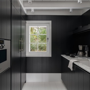 Prepare your favorite meals in this sleek galley kitchen featuring premium appliances, marble countertops, and charming garden views through the window.