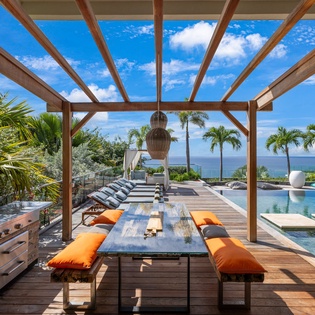Dine under your private pergola with ocean views and tropical palms framing this stunning outdoor living space.