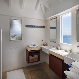 Your spacious bathroom features dual sinks and stunning ocean views, combining elegant design with the soothing presence of the sea just beyond your window.