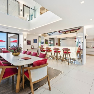 Gather around this stunning open-concept dining area where modern elegance meets comfort, featuring vibrant red accents and panoramic views.