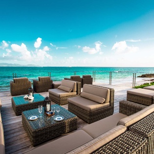 This oceanfront terrace features plush seating with stunning turquoise waters and a pristine beach just steps away, offering a serene coastal escape.