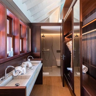 Your private spa-style bathroom features rich wood cabinetry, dual vanities, a walk-in shower, and plush towels—a luxurious retreat for unwinding.