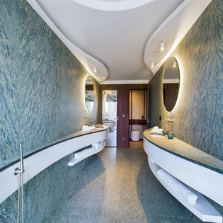 Step into your spa-like sanctuary with stunning ocean-blue walls, dual vanities, and a curved soaking tub—your private retreat awaits.