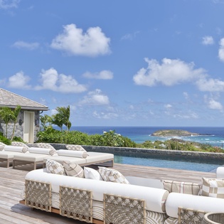 Luxury oceanfront pool deck featuring elegant loungers and stunning sea views across tropical Caribbean waters.