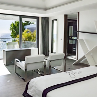 Your sophisticated suite features modern architecture with stunning sea views from expansive windows. Relax in sleek seating while ocean breezes drift through.